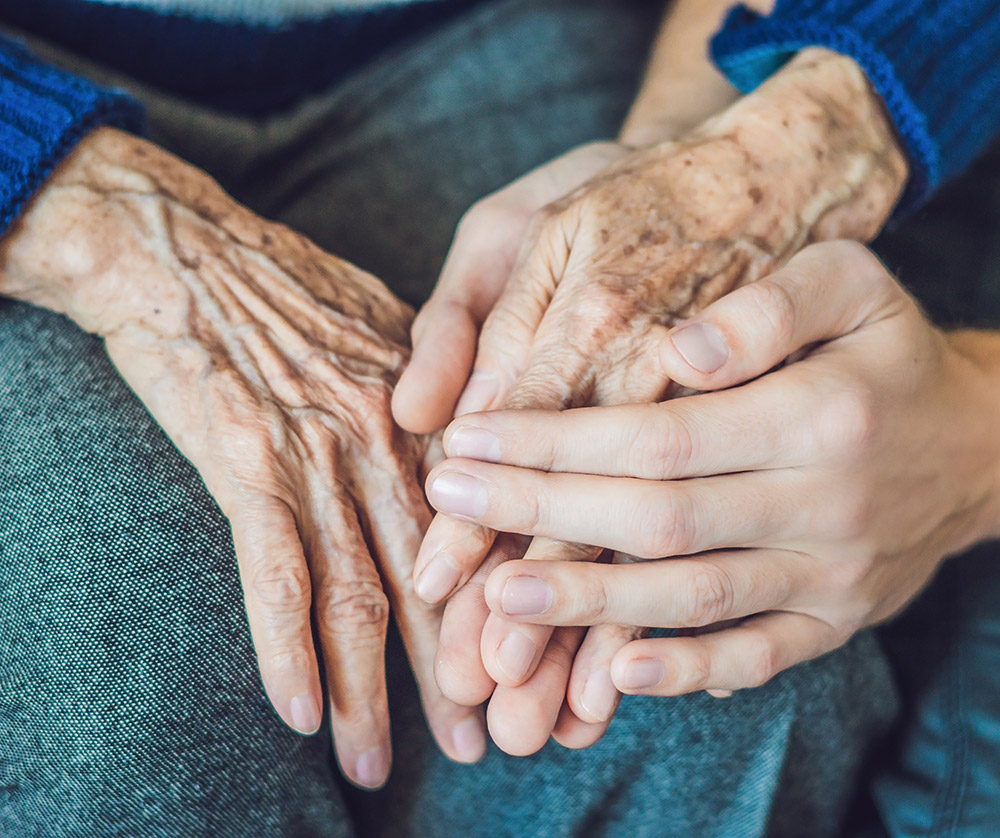 younger hands holding elderly hands