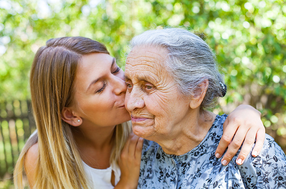Younger woman kissing the cheek of an elderly woman