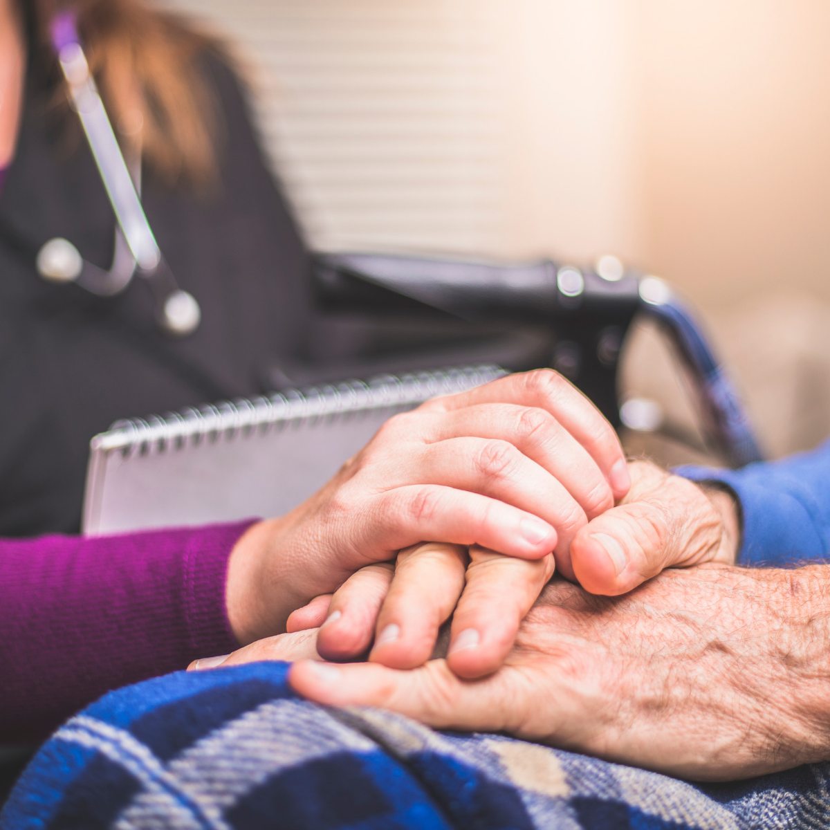 hospice nurse hand on top of patient holding a notebook